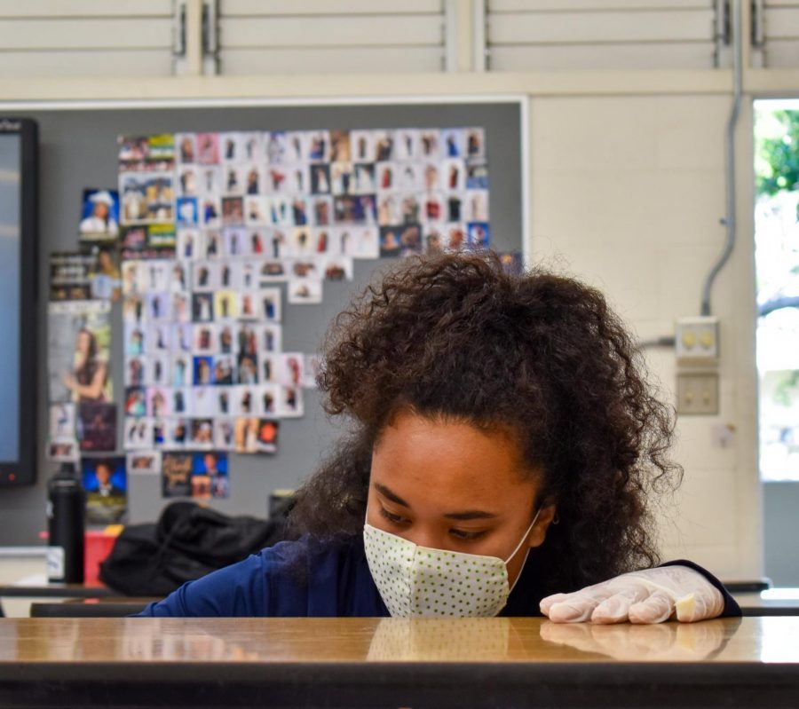 Sophomore Jasmine Adiniwin cleans desks for campus beautification.