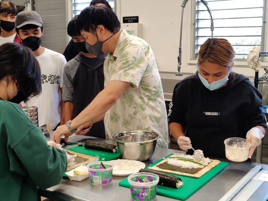 Mitsuda demonstrates rolling technique to the sushi  team.