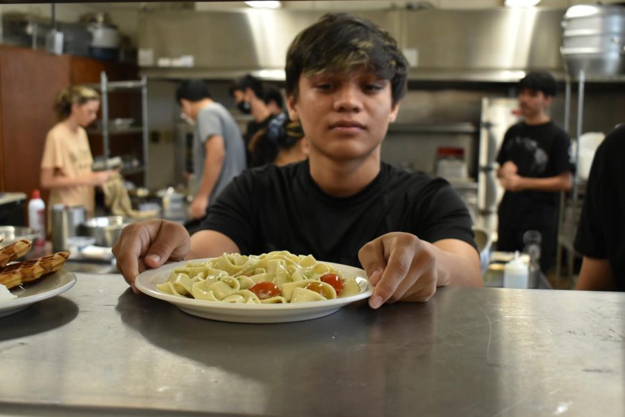 Diego Flores places the pasta onto the shelf for the servers to take out to the front of the house.