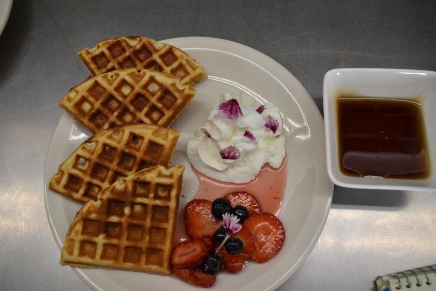 Yeast waffle with fresh berries, cream and edible flowers.