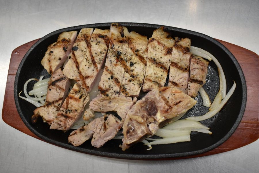 Brined and grilled pork chop with sizzling onions.