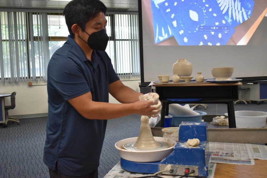 Ceramics teacher Makana Wong demonstrate the wheel to students interested in a fine arts elective.