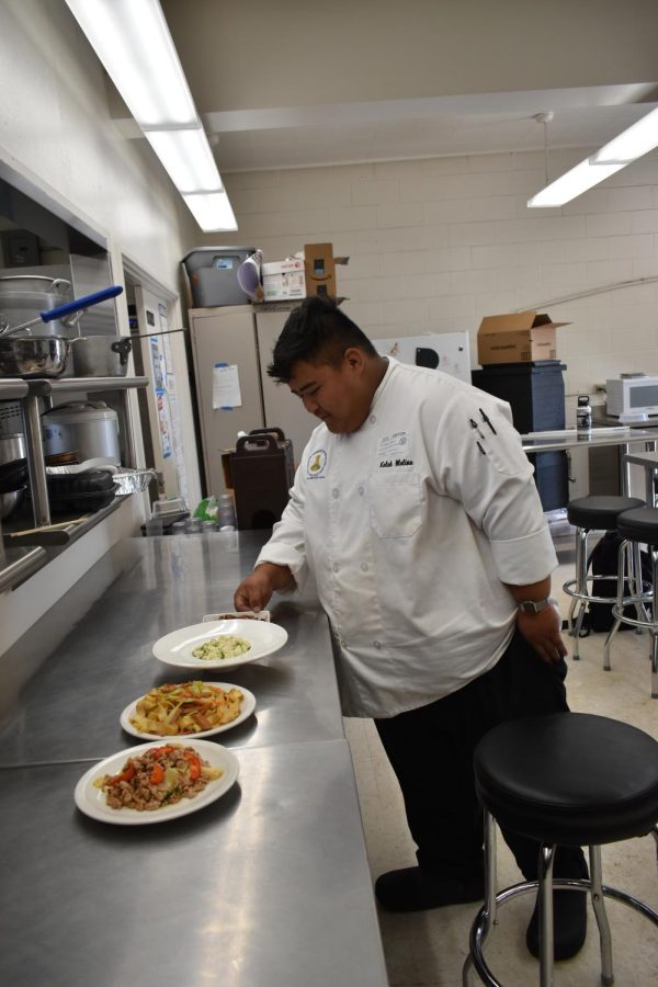 Alumni and chef Kaleb Molina inspects the three dishes the culinary II class prepared for him. 