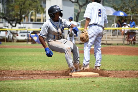 Rayden Migueal kicks up some dirt as he breaks hard into third base.