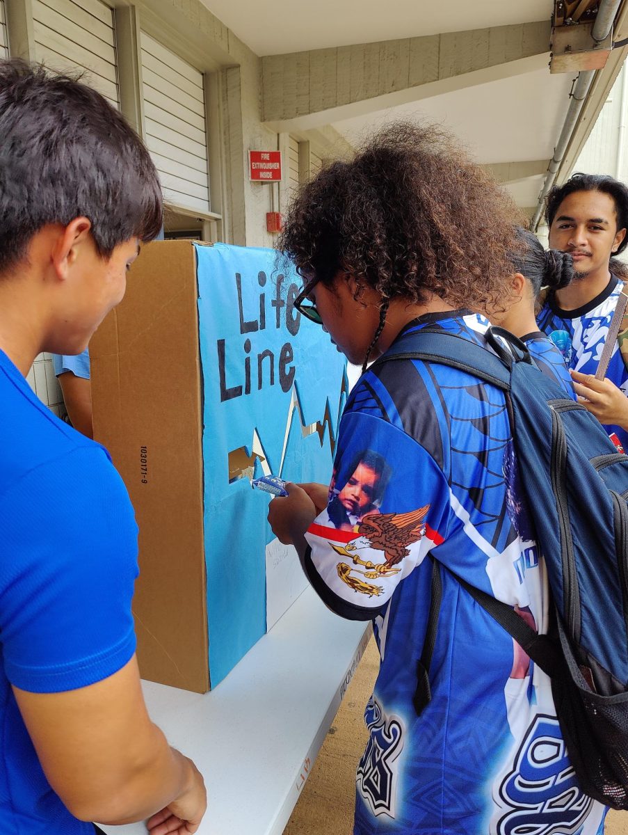 Giovanni Leota tries his hand at the Life Line activity booth designed by Ryder Park. Leotas challenge was to answer true/false questions about suicide while trying to move the rule through the openings in the display board without touching the sides. Anyone experiencing a crisis can call 988, and it will route them to the National Suicide Prevention hotline.