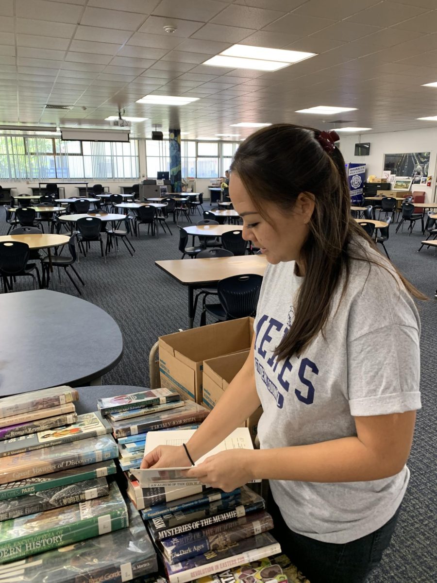 Library Manager Maggie Travers carefully arranges the non-fiction books the library is giving away on the front table by the entrance. Students have until the end of October to take what they want. 