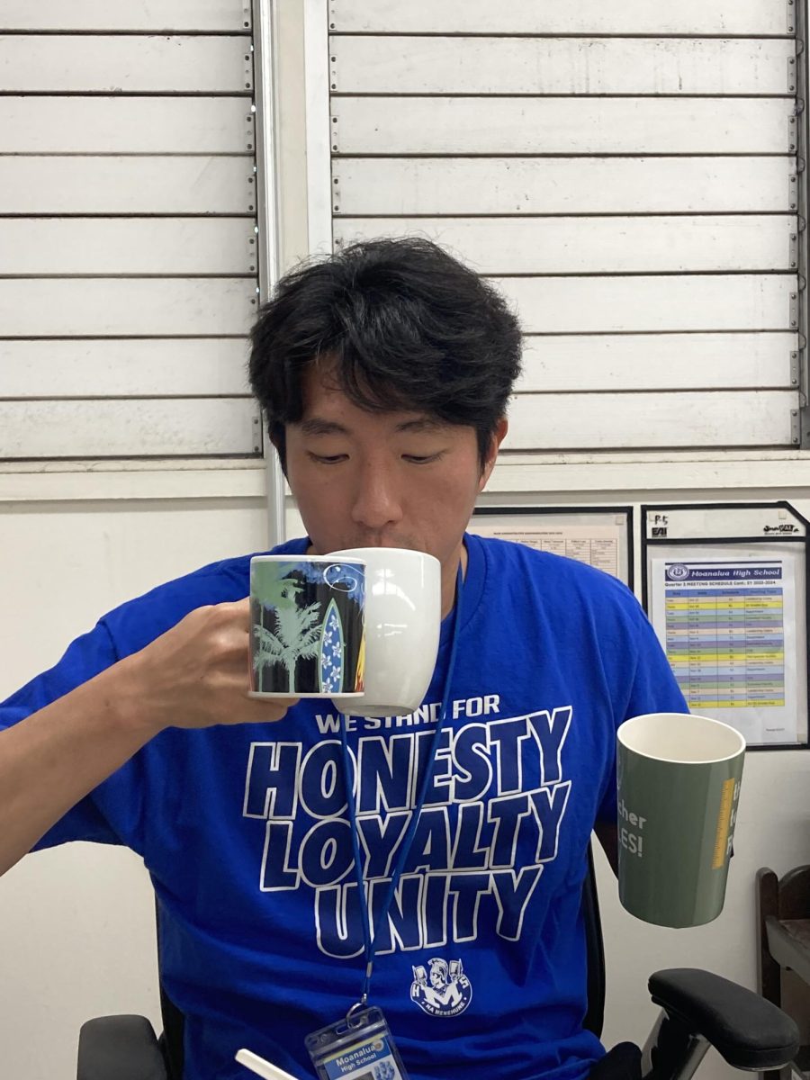 Parks poses with his coffee cup collection, that piles up in the corner next to his desk. Many of the cups are gifts from his students or friends, in honor of his coffee consumption.