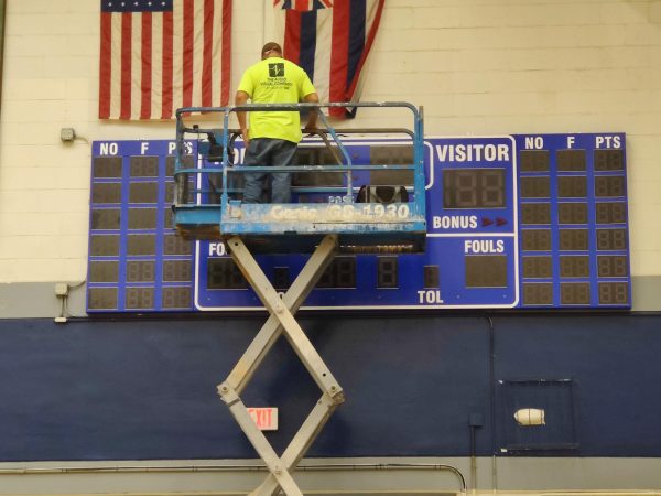 A worker installs one of two new scoreboards with shot panels in the school gym during exam week. It will be ready to go when Moanalua girls play Farrington Dec. 27.